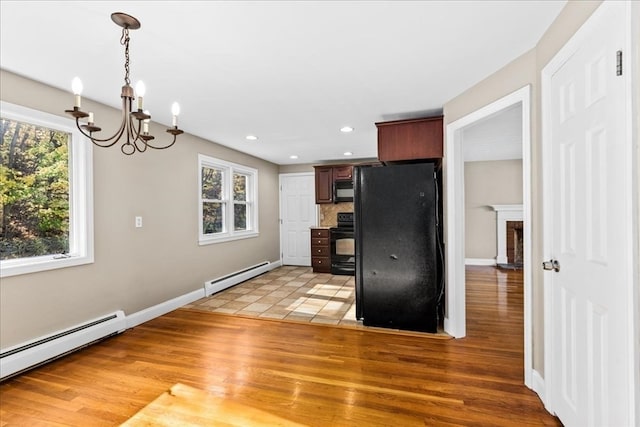 kitchen with decorative backsplash, black appliances, light hardwood / wood-style floors, and baseboard heating