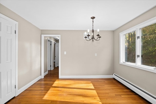 unfurnished dining area featuring baseboard heating, an inviting chandelier, and hardwood / wood-style floors