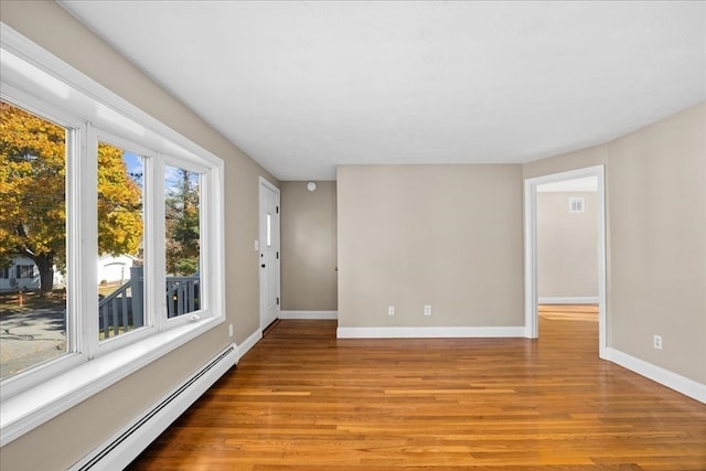 unfurnished room featuring baseboard heating and light hardwood / wood-style flooring