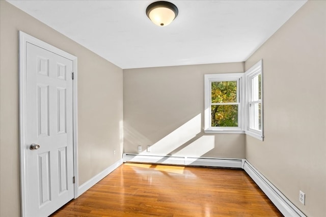 unfurnished room featuring hardwood / wood-style flooring and a baseboard radiator