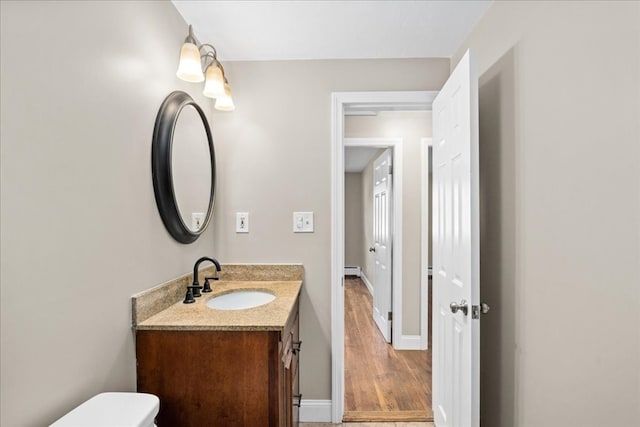 bathroom with hardwood / wood-style flooring, vanity, and toilet