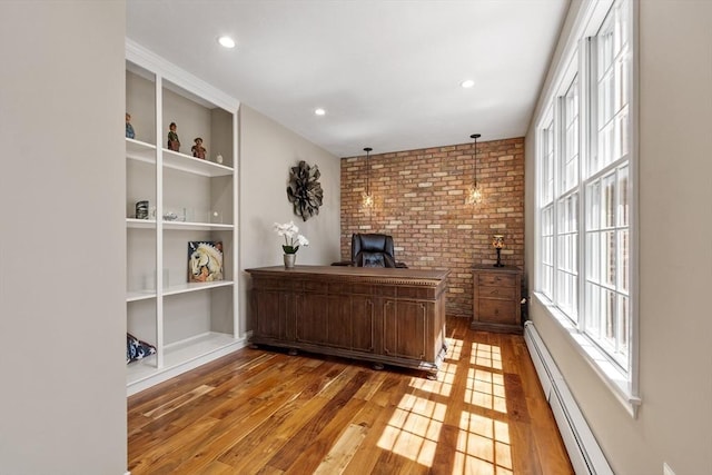 office featuring brick wall, built in features, wood-type flooring, a baseboard heating unit, and recessed lighting