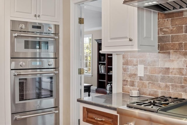 kitchen featuring double oven, wall chimney exhaust hood, a warming drawer, and white cabinetry