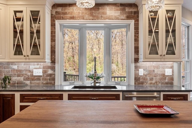 bar with stainless steel dishwasher, a chandelier, and decorative backsplash