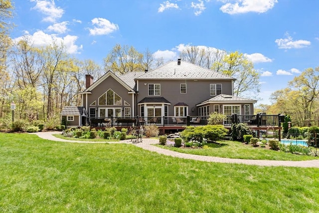 back of house with a fenced in pool, a wooden deck, and a chimney