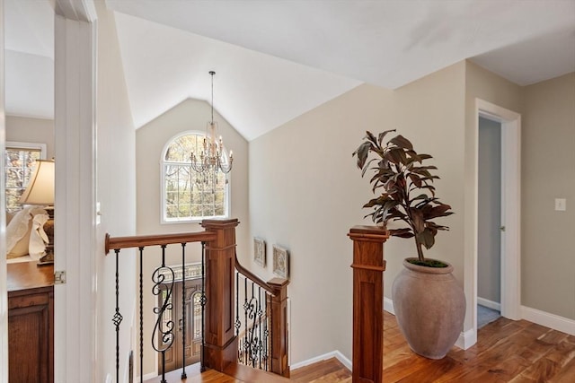 interior space with an inviting chandelier, baseboards, lofted ceiling, and wood finished floors