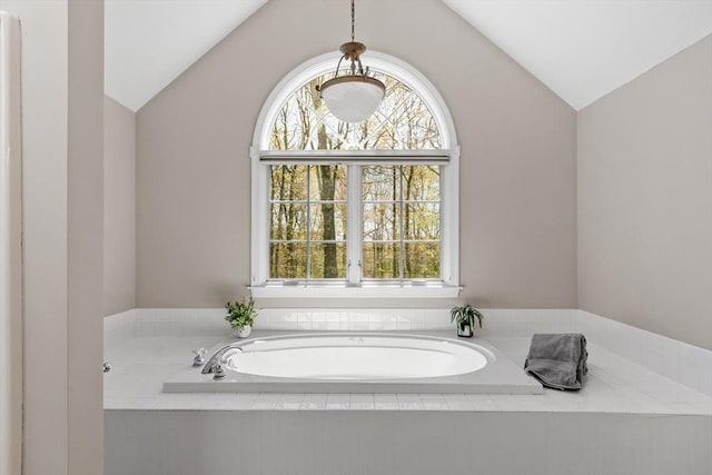 bathroom featuring vaulted ceiling, plenty of natural light, and a bath