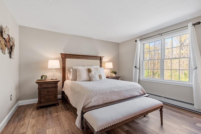 bedroom featuring baseboard heating, baseboards, and wood finished floors