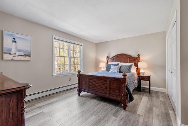bedroom with baseboards, a baseboard radiator, wood finished floors, and a closet