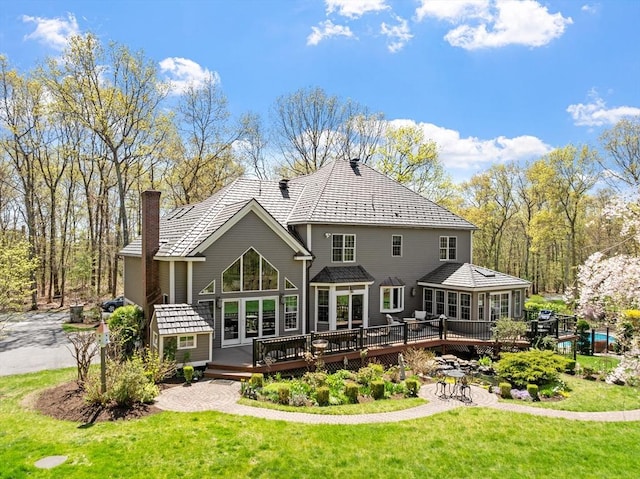 rear view of property with a yard, a wooden deck, and a chimney
