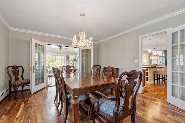 dining space with french doors, crown molding, a chandelier, and hardwood / wood-style flooring