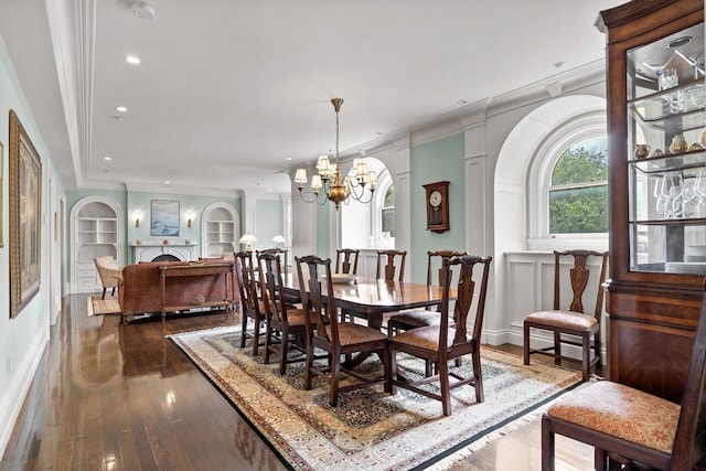 dining room featuring built in features, wood-type flooring, an inviting chandelier, and crown molding