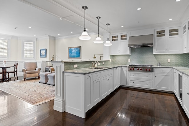 kitchen featuring stainless steel gas stovetop, wall chimney exhaust hood, kitchen peninsula, and white cabinetry