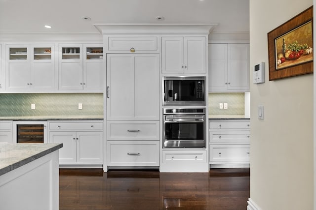 kitchen featuring white cabinetry, decorative backsplash, stainless steel oven, and black microwave