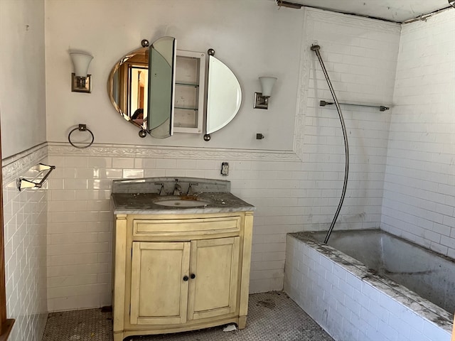 bathroom with tile patterned flooring, tile walls, vanity, and tiled shower / bath