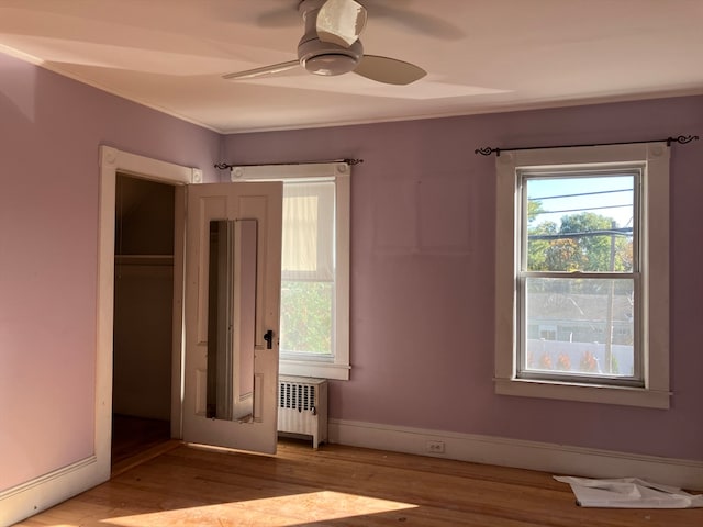 unfurnished bedroom featuring ceiling fan, a closet, light hardwood / wood-style floors, and radiator heating unit