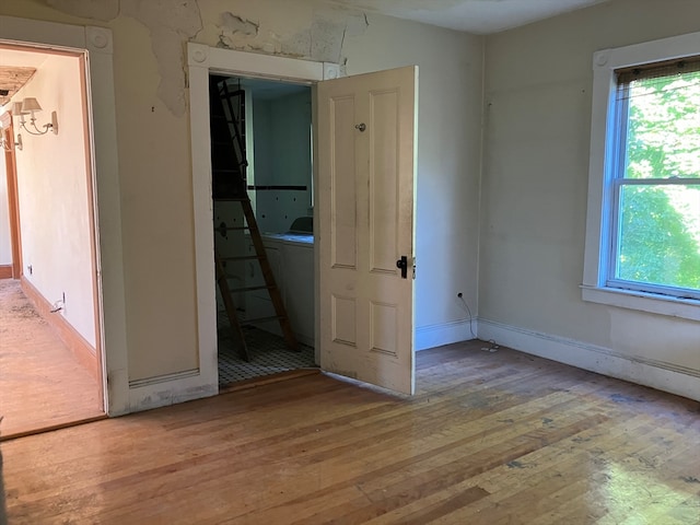 empty room featuring plenty of natural light, light hardwood / wood-style floors, and stacked washer and dryer