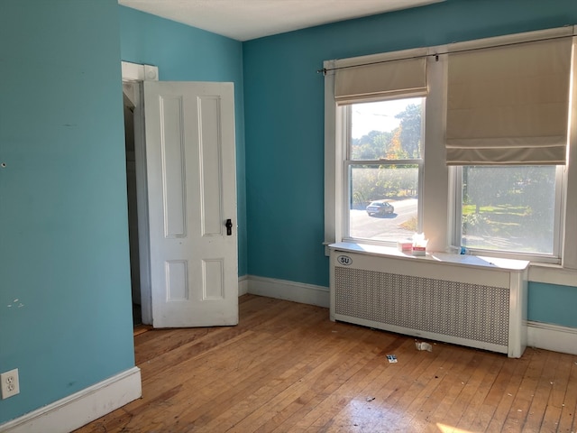 spare room featuring radiator and light hardwood / wood-style flooring