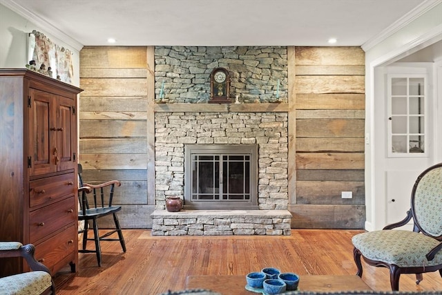 living room featuring crown molding, wood walls, wood finished floors, and a fireplace