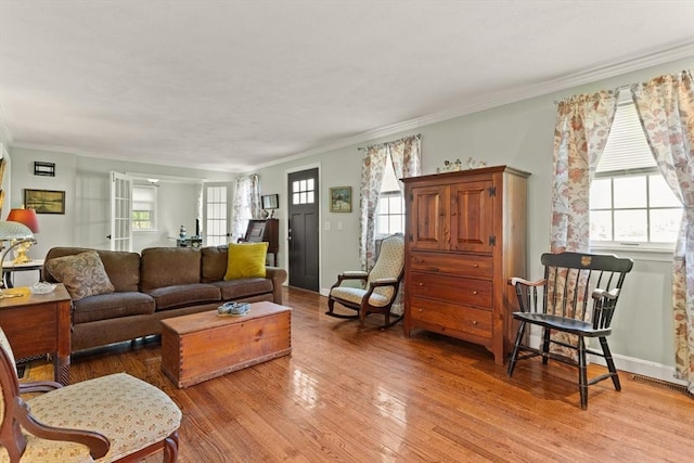 living area featuring baseboards, ornamental molding, and light wood finished floors