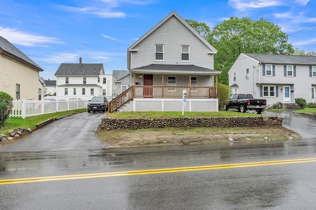 view of front of home featuring a porch, fence, a residential view, and asphalt driveway