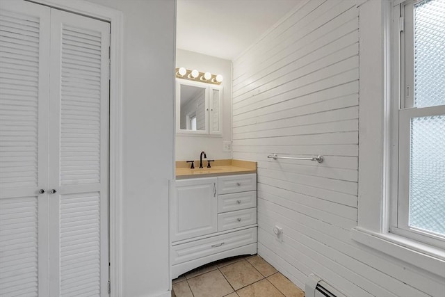 bathroom featuring wood walls, tile patterned floors, vanity, baseboard heating, and healthy amount of natural light
