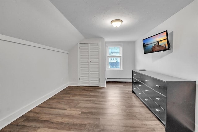 bonus room with a baseboard heating unit, vaulted ceiling, wood finished floors, and baseboards