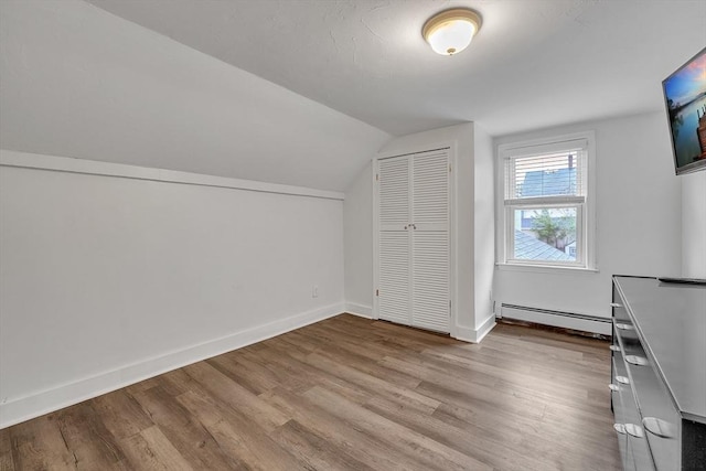 bonus room featuring baseboard heating, lofted ceiling, wood finished floors, and baseboards