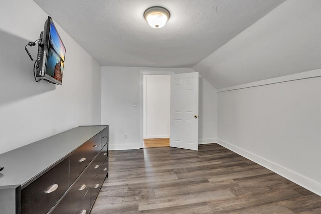 additional living space with dark wood-style flooring, baseboards, and lofted ceiling