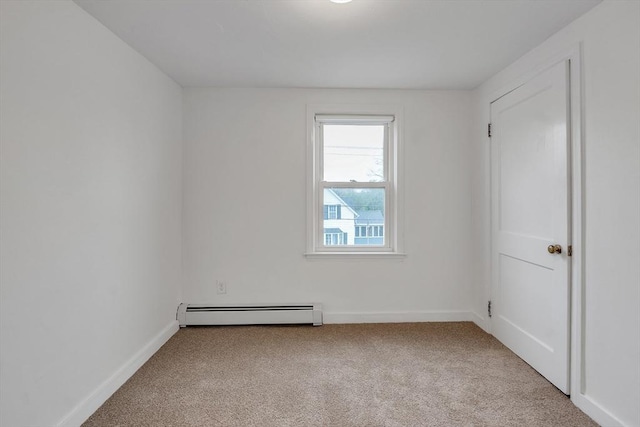spare room featuring baseboard heating, light carpet, and baseboards