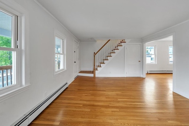 spare room featuring baseboard heating, a baseboard heating unit, crown molding, stairway, and plenty of natural light