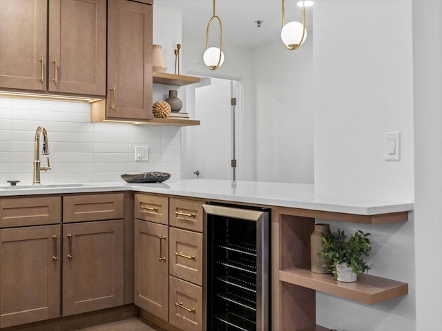 kitchen featuring backsplash, wine cooler, sink, and pendant lighting