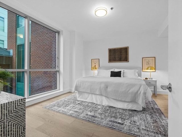 bedroom with light hardwood / wood-style floors and a wall of windows