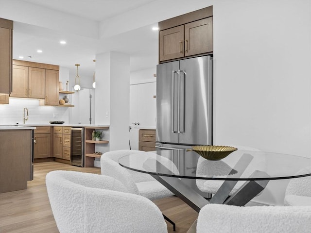 dining room featuring light wood-type flooring, wine cooler, and sink