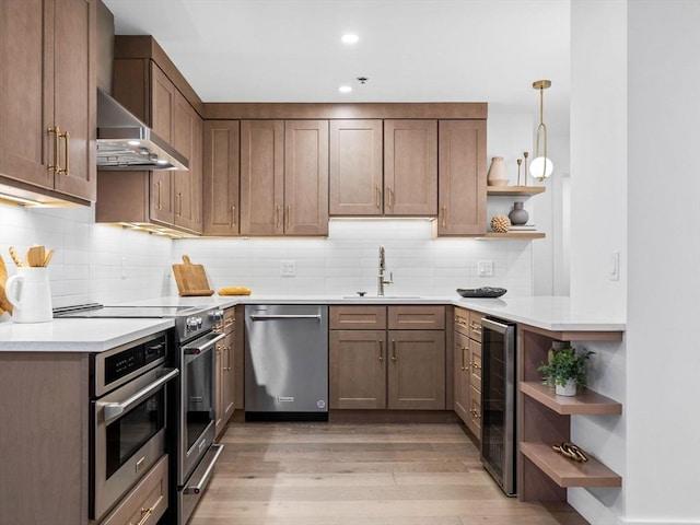 kitchen with sink, hanging light fixtures, wine cooler, light hardwood / wood-style floors, and appliances with stainless steel finishes