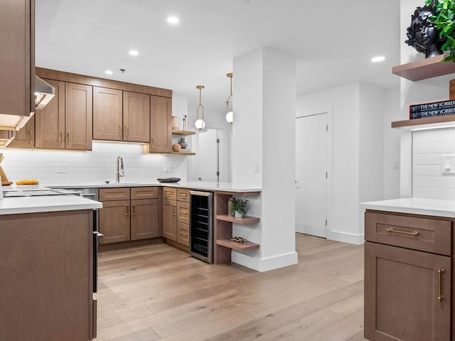 kitchen featuring pendant lighting, decorative backsplash, wine cooler, and light hardwood / wood-style flooring