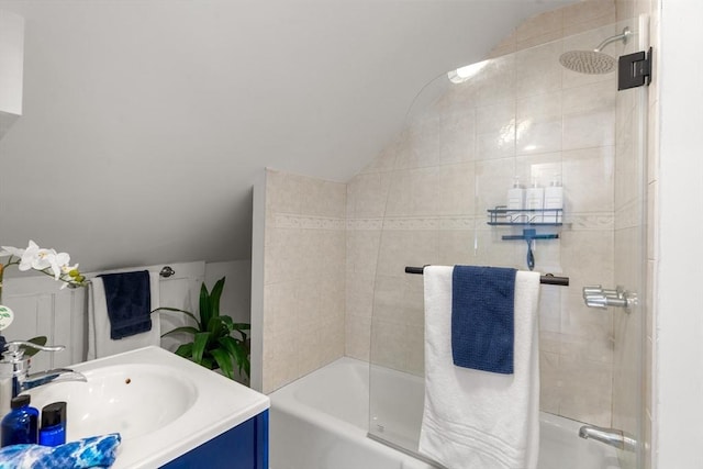 bathroom featuring tiled shower / bath combo, vaulted ceiling, and vanity