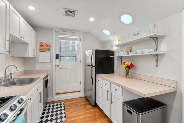 kitchen featuring sink, light hardwood / wood-style flooring, white cabinetry, stainless steel appliances, and decorative backsplash