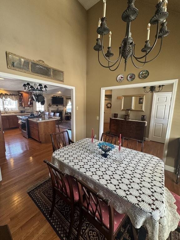 dining space with baseboards, dark wood finished floors, a towering ceiling, and an inviting chandelier