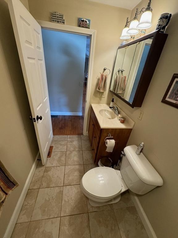 bathroom with toilet, tile patterned floors, vanity, and baseboards