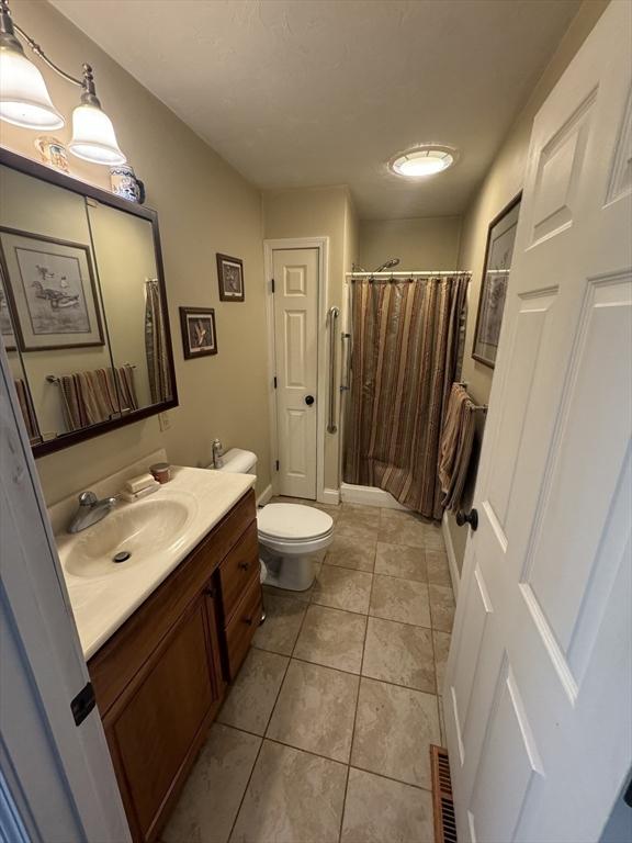 bathroom with visible vents, toilet, tile patterned floors, curtained shower, and vanity