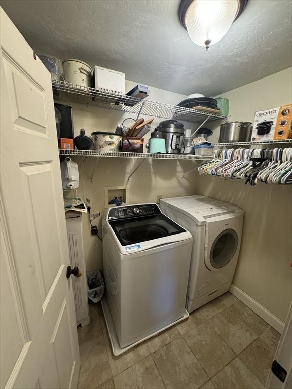 laundry room featuring a textured ceiling, laundry area, and washing machine and clothes dryer