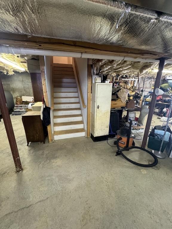 unfinished basement featuring stairway and heating fuel