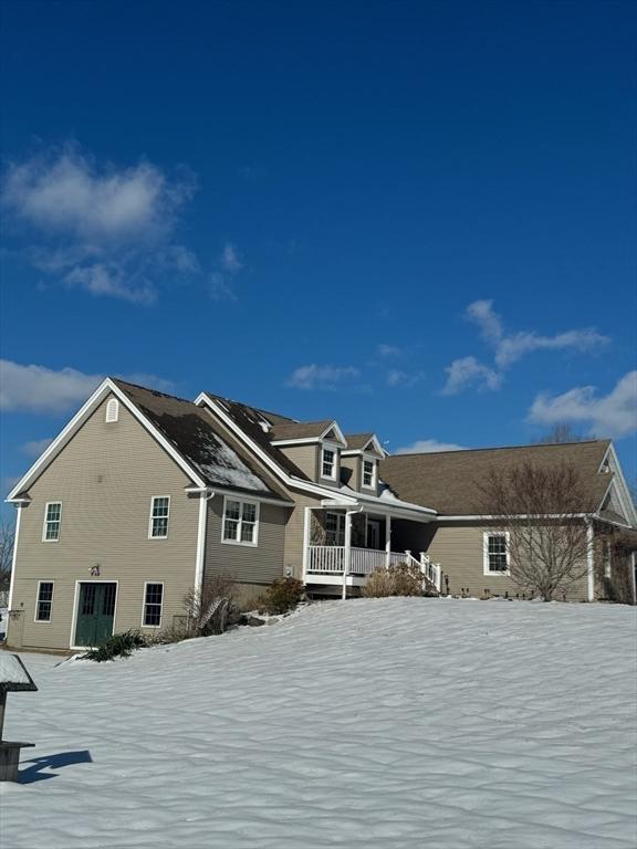 snow covered rear of property featuring a porch