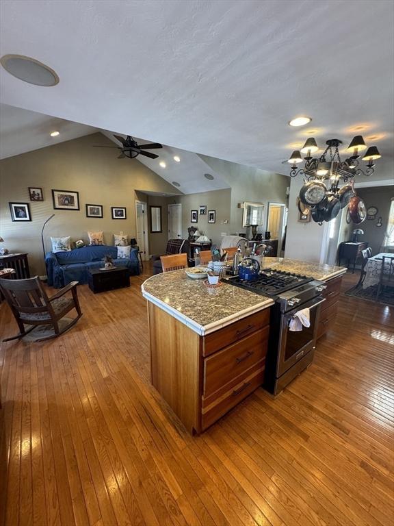 kitchen featuring gas range, a kitchen island, open floor plan, and wood finished floors