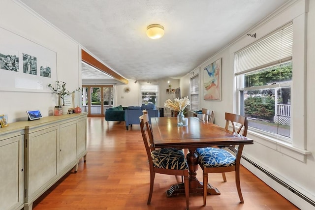 dining area with baseboard heating, ornamental molding, light wood-type flooring, and french doors