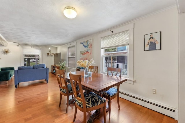 dining space featuring light hardwood / wood-style floors, a baseboard heating unit, and ornamental molding