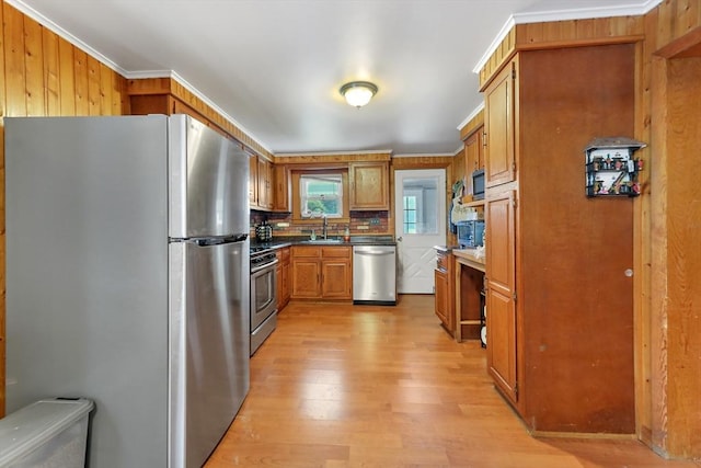 kitchen with stainless steel appliances, light hardwood / wood-style flooring, sink, ornamental molding, and backsplash