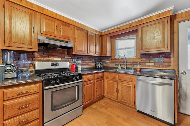 kitchen with sink, backsplash, dark stone counters, light hardwood / wood-style floors, and stainless steel appliances