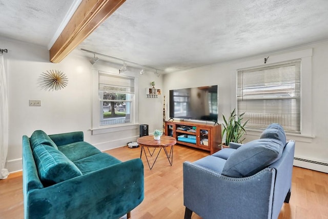 living room featuring rail lighting, beamed ceiling, a baseboard heating unit, a textured ceiling, and light hardwood / wood-style floors